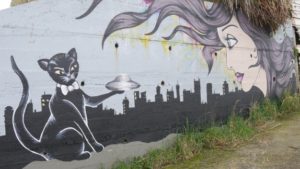 Wall mural showing a black cat holding a flying saucer out to a woman's head.