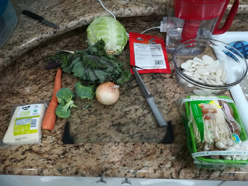 Ingredients for Hot Pot Soup including Mushrooms, tofu, carrots, broccoli, kale, cabbage, water, rice cakes, and 'hot pot' soup mix